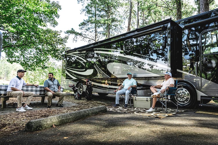 Thor motor coach parked at a camp site with friends having a conversation while grilling food