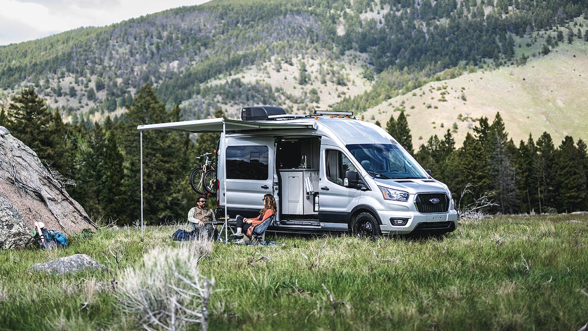 Tranquility Transit Van in Montana beside mountains with people relaxing outside