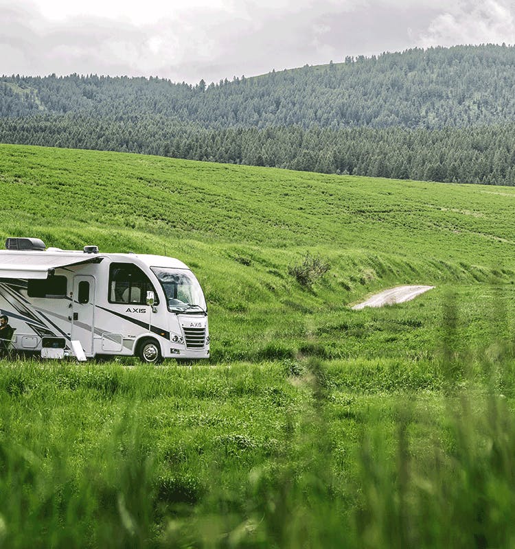 2024  Axis Class A Motorhome in open grassy area with woods and mountains behind