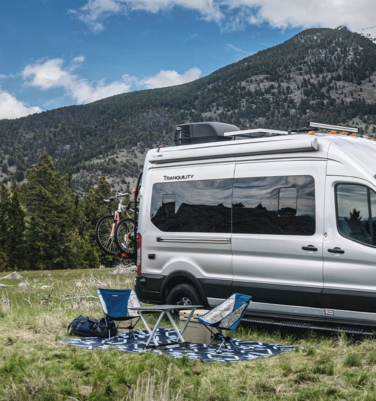 Tranquility Ford Transit boondocking in Montana with mountains behind