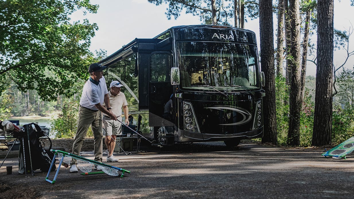 Men golfing in front of an Aria Class A Motorhome