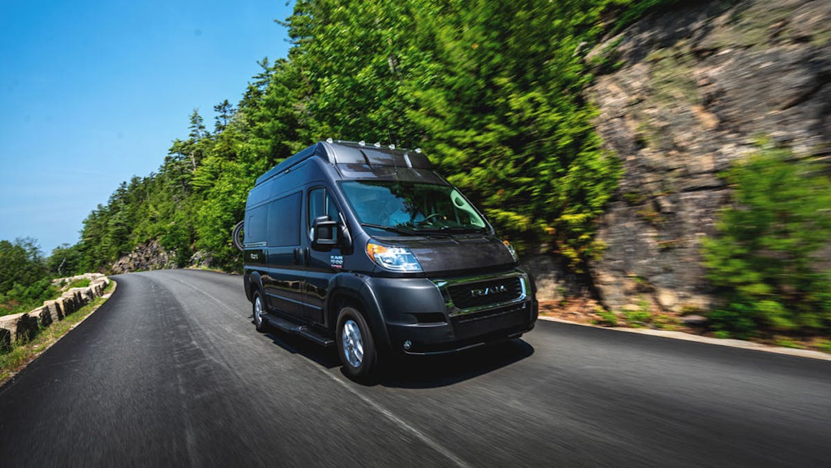 Thor Scope Class B Camper Van driving on the road beside tall cliff